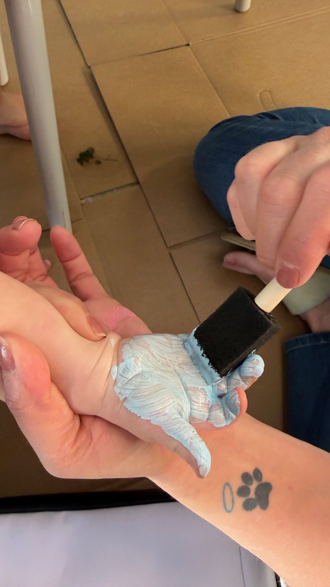 parent applying blue paint to child’s hand for The Stever Co Mom’s Favorite handprint tote