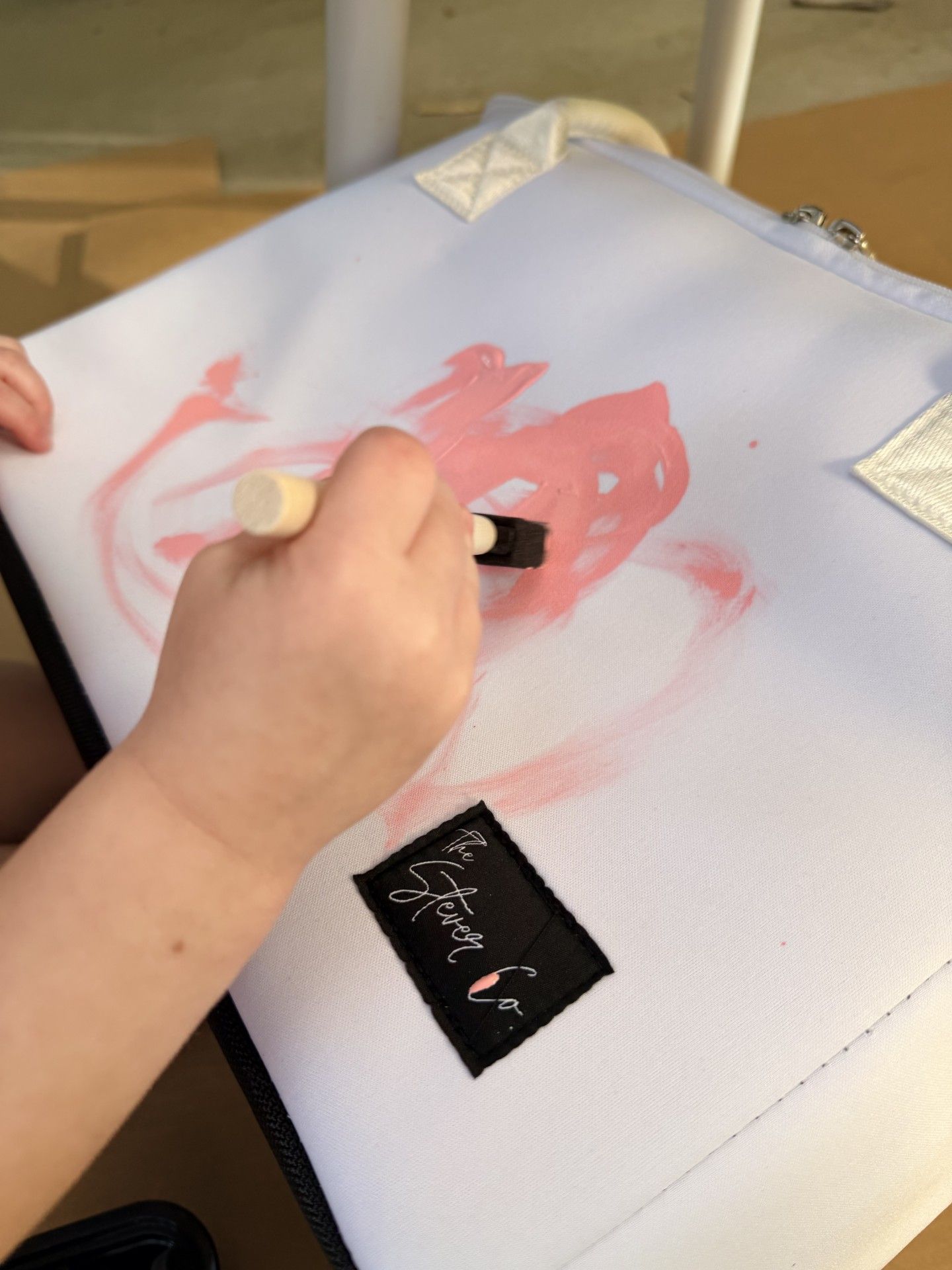 child painting The Stever Co Mom’s Favorite insulated tote with pink paint for Mother’s Day gift