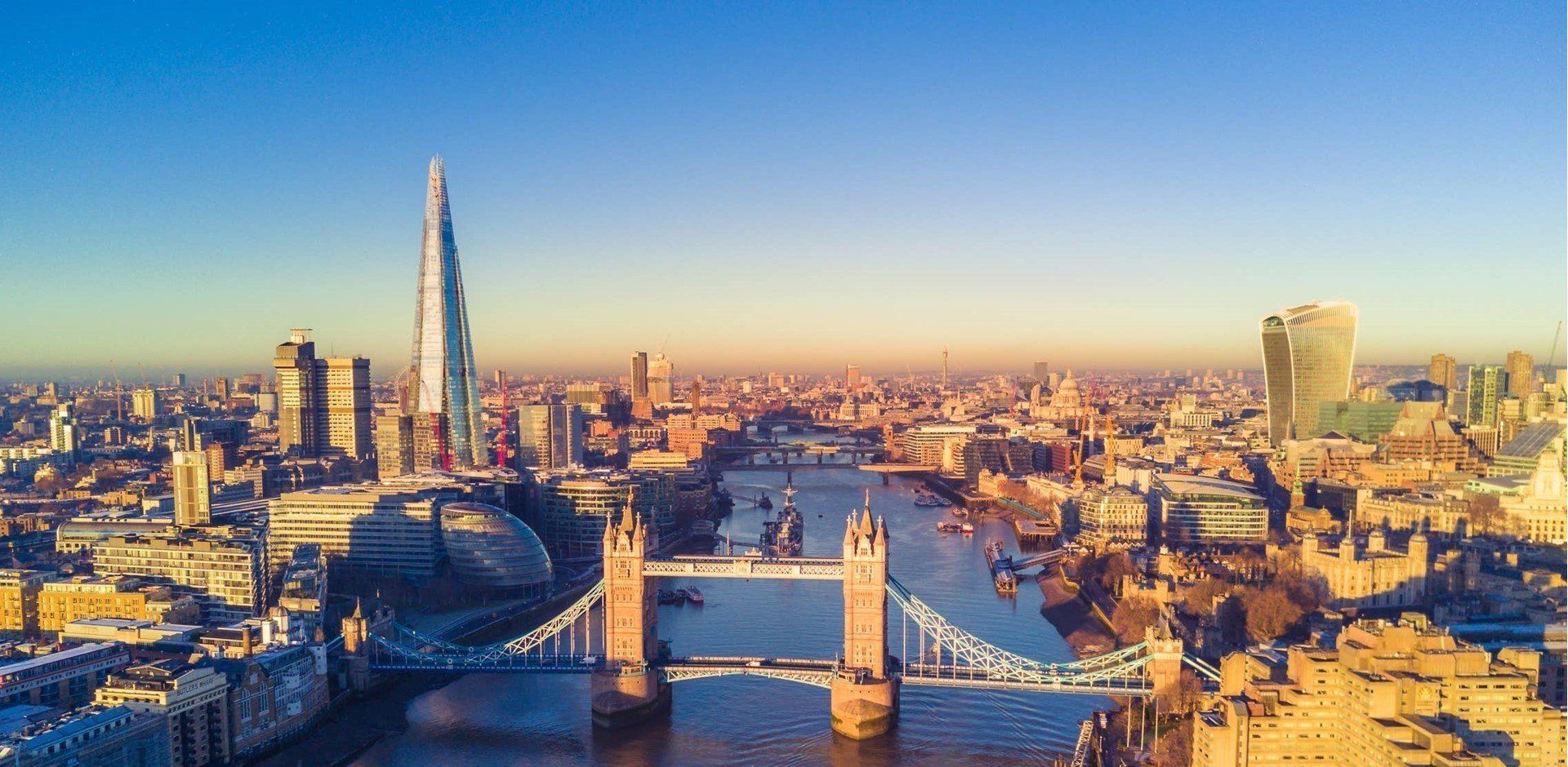 Vista aérea do Rio Tâmisa e da Tower Bridge em Londres, com o arranha-céu The Shard ao pôr do sol.
