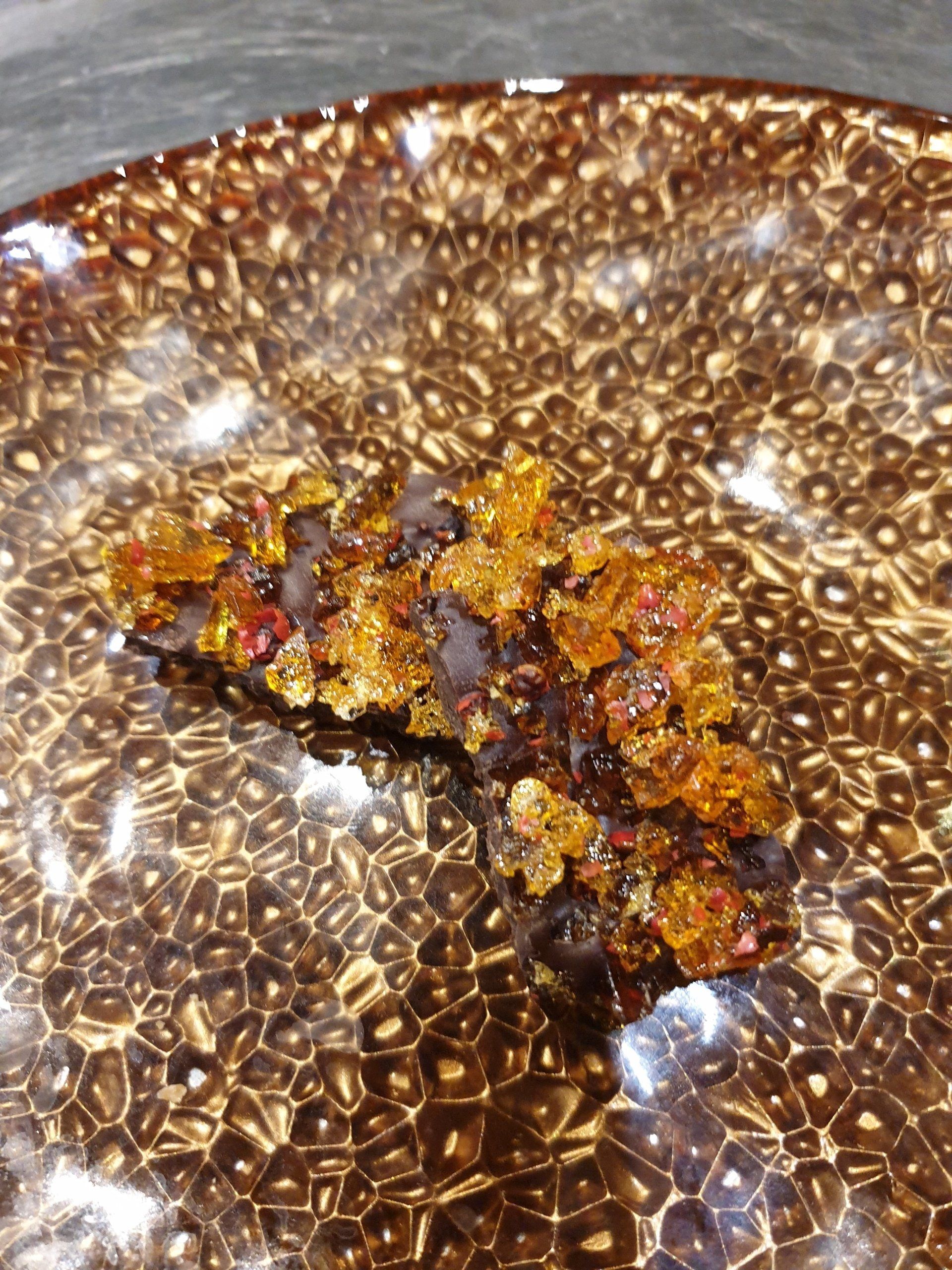 Dark chocolate topped with candied orange pieces on a patterned plate.