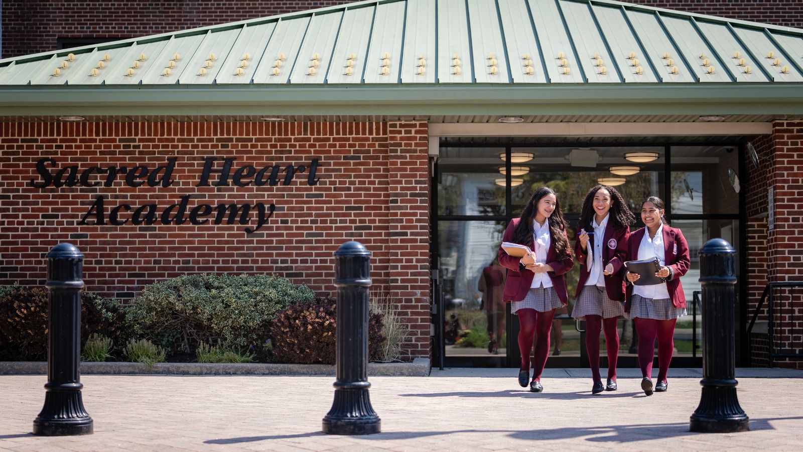 Three Sacred Heart Academy students walking out of the building's main office