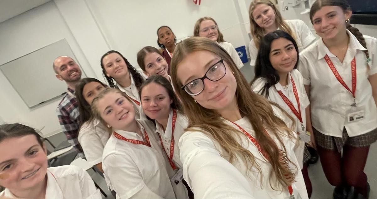 A group of young women are posing for a selfie in a classroom.