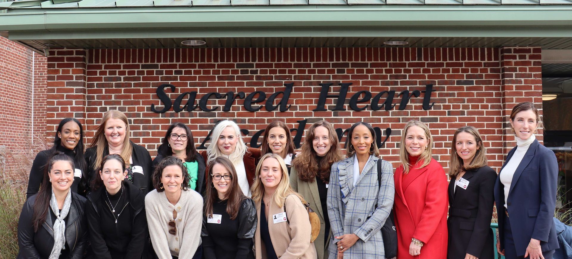 15 Sacred Heart Academy Alumnae posing for a photo outside the school