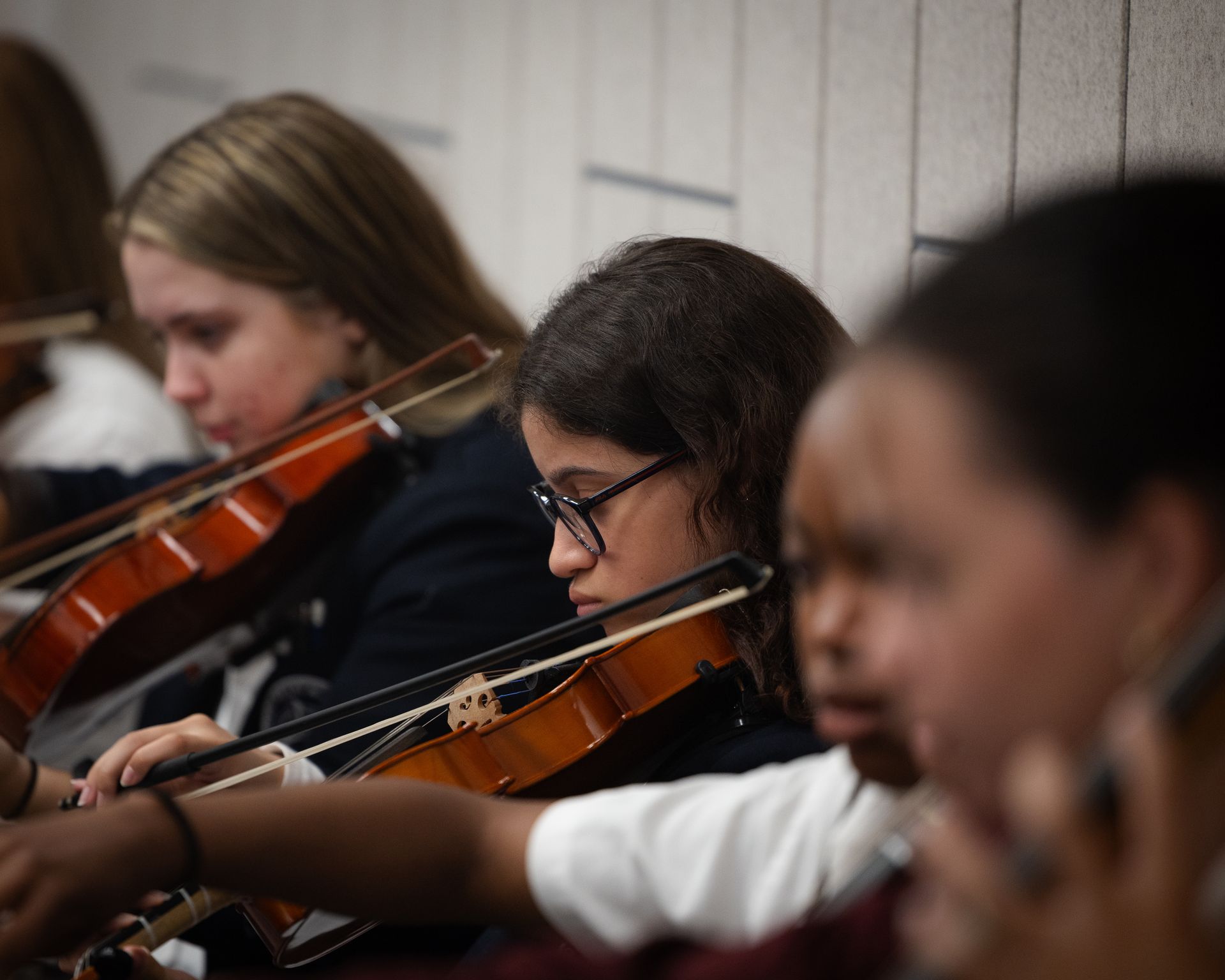 A group of young girls are playing violins in an orchestra