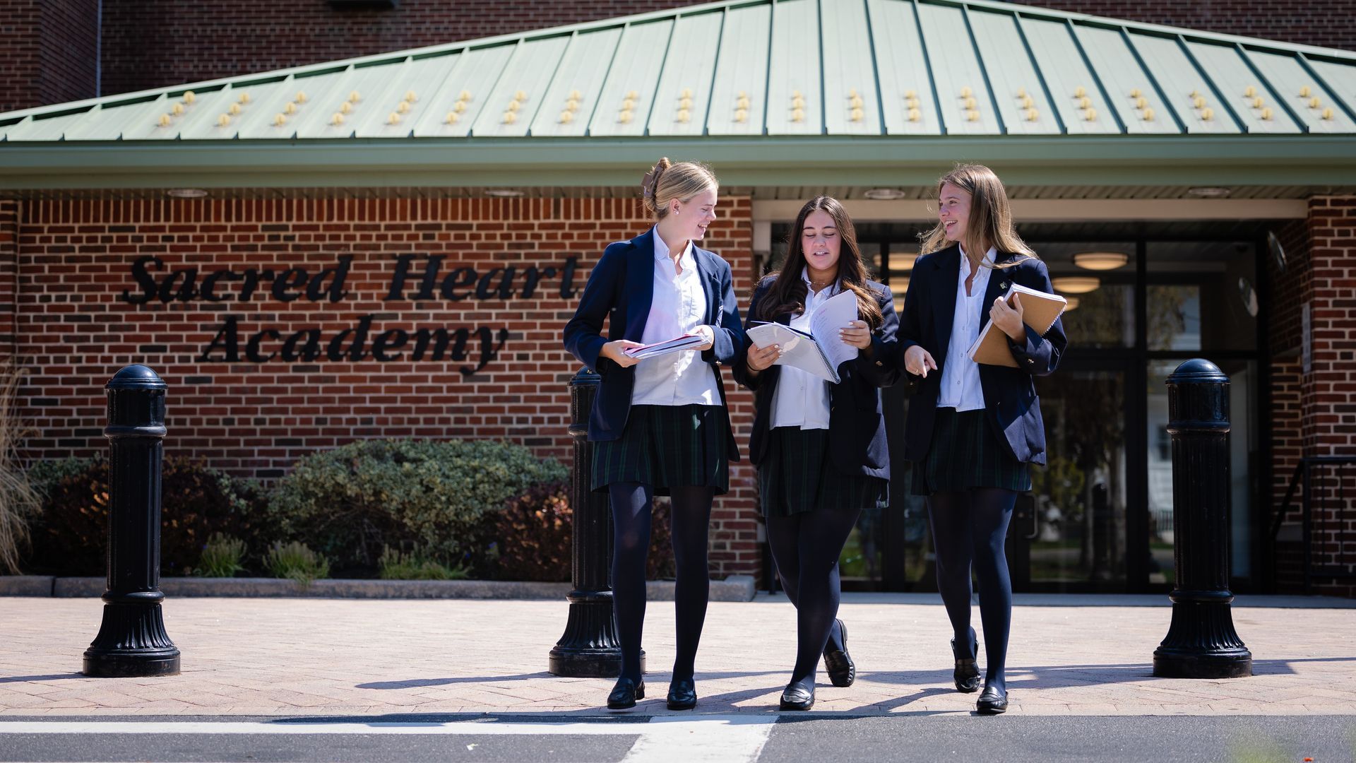 A group of girls are walking in front of the sacred heart academy