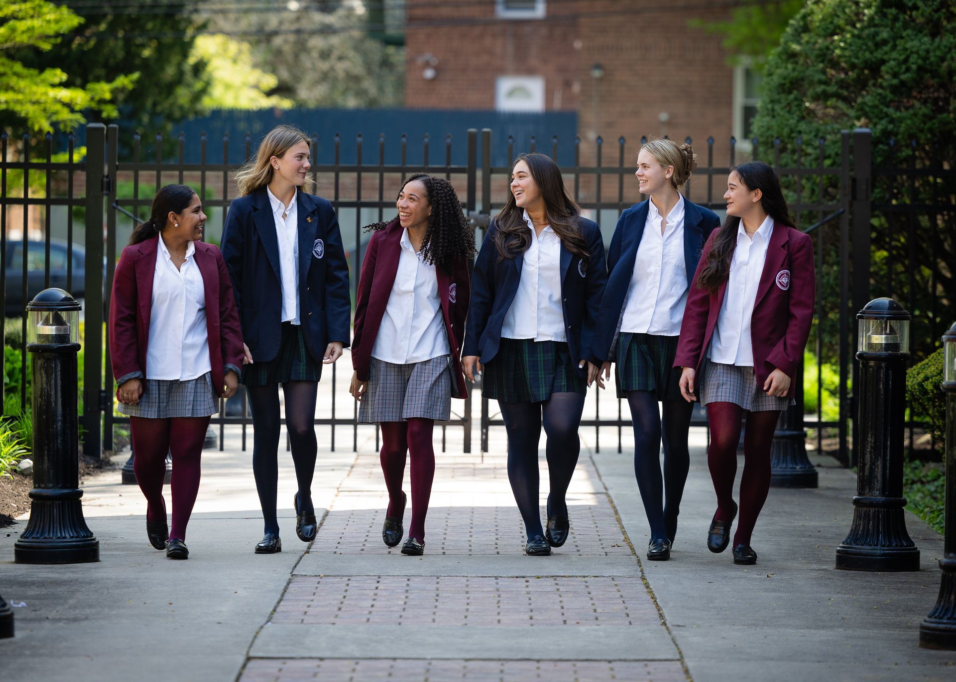 A group of girls in school uniforms are walking down a sidewalk