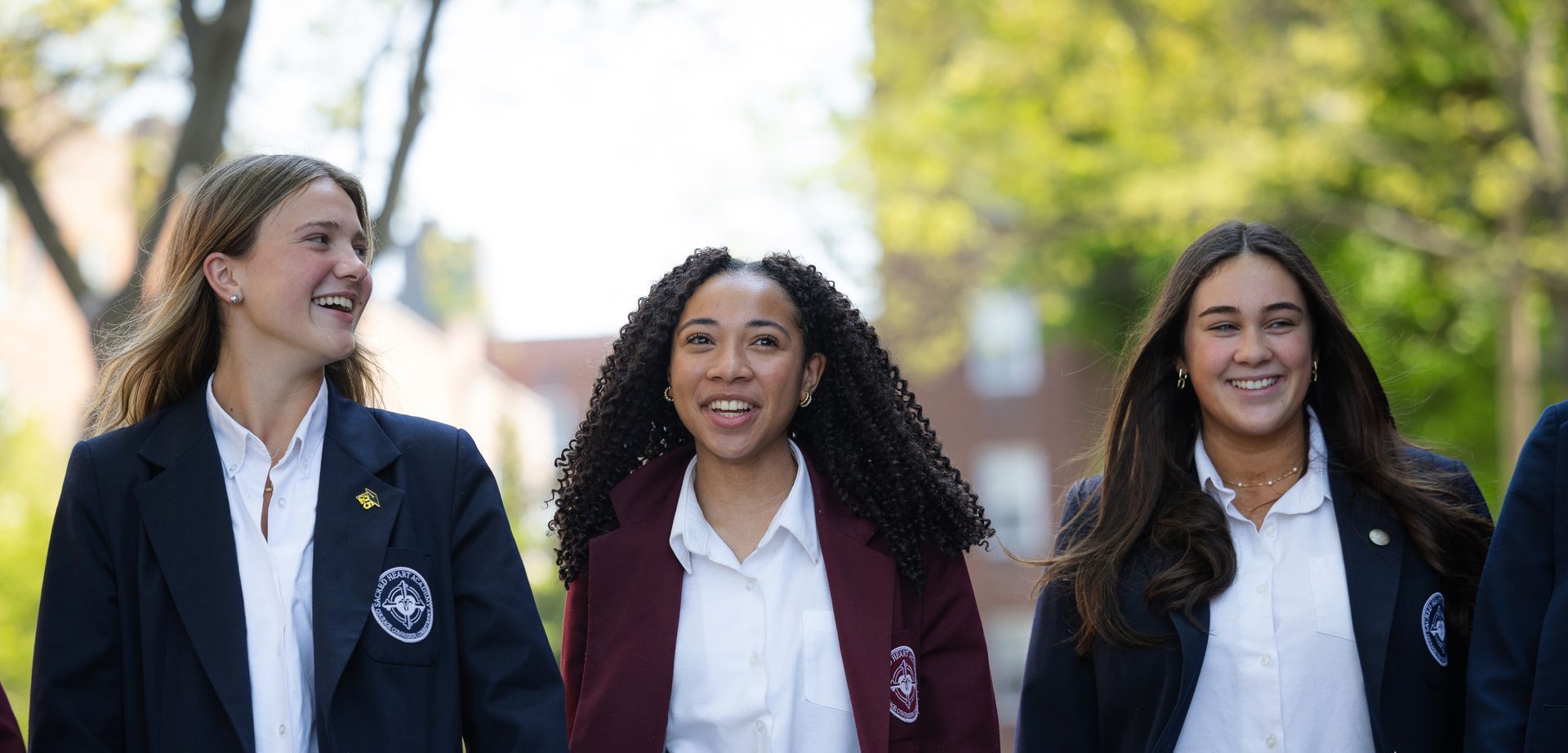 Three girls in school uniforms are walking together and smiling