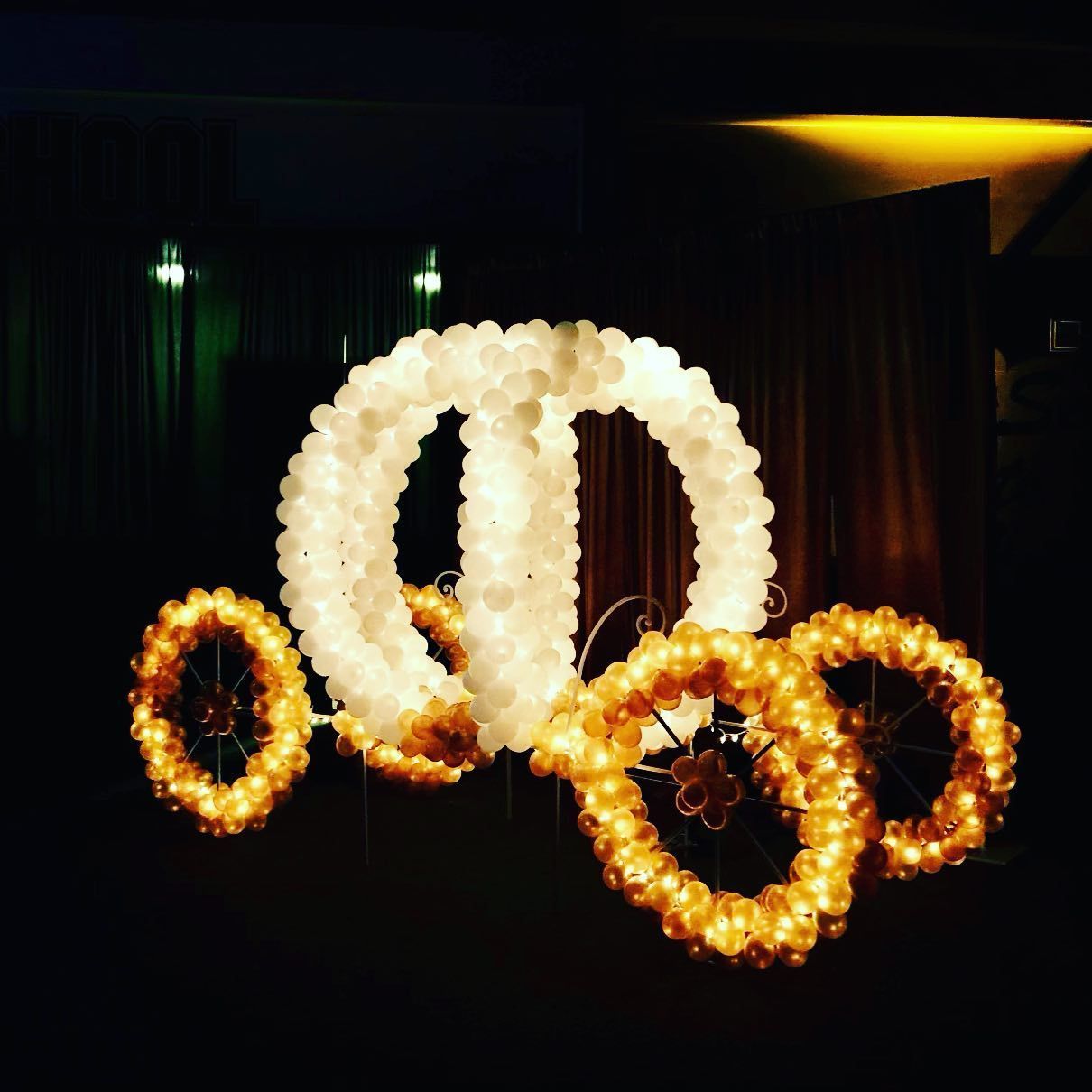 A lighted, glowing carriage made of orbs, with wheels and body, suspended in the dark.