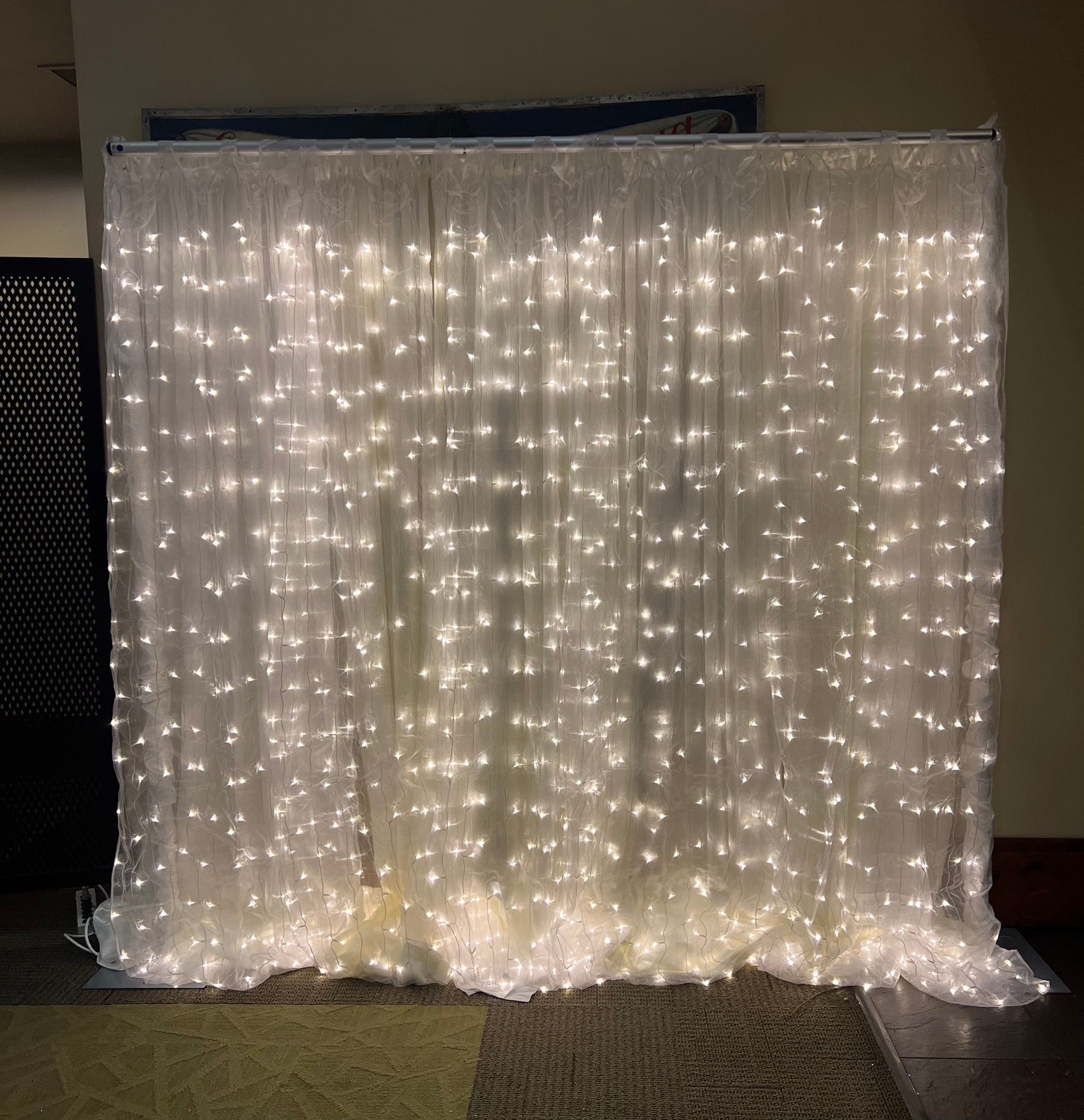 White curtain with twinkling fairy lights against a wall.