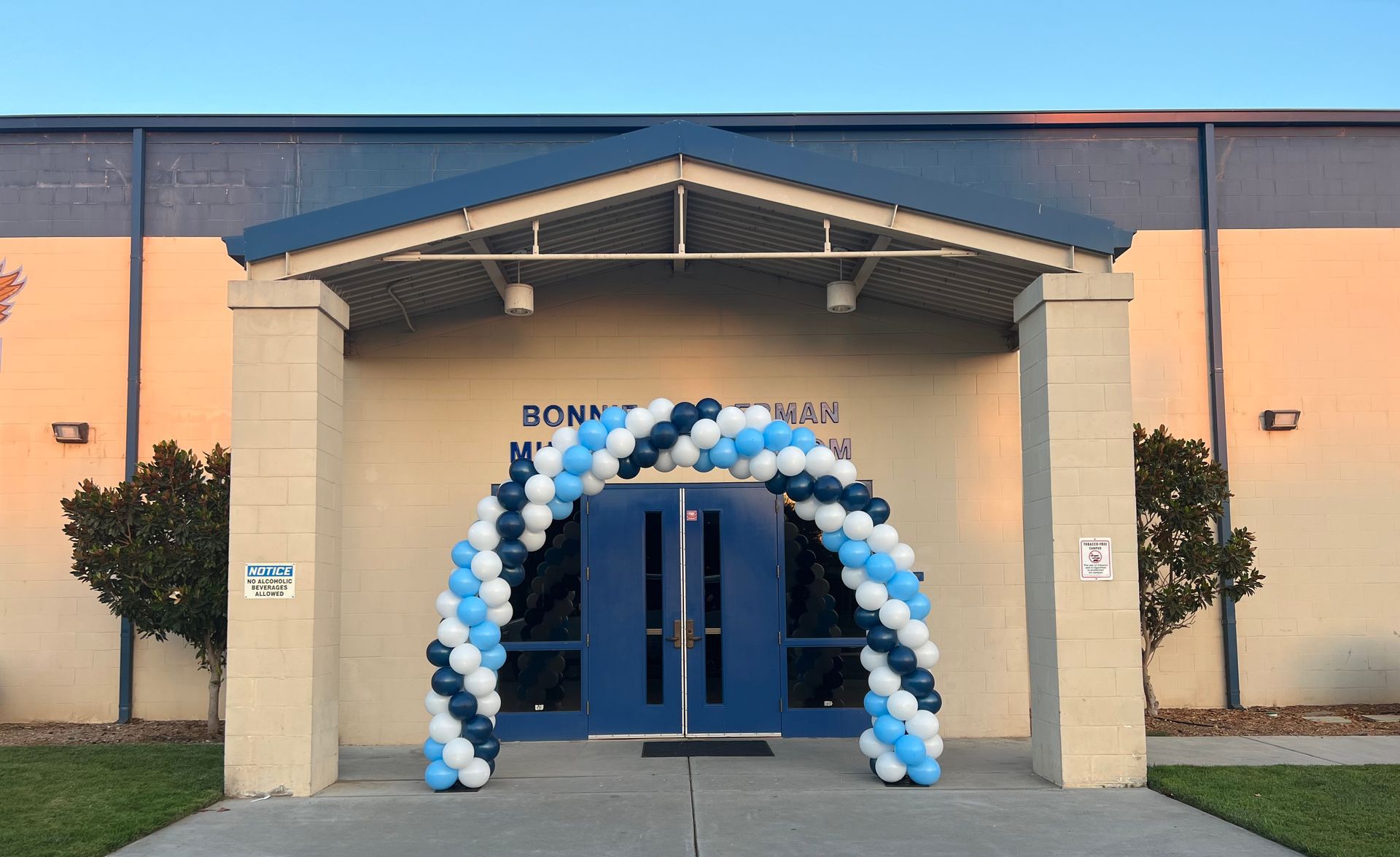 Entrance of a school with a blue and white balloon arch over the double doors.