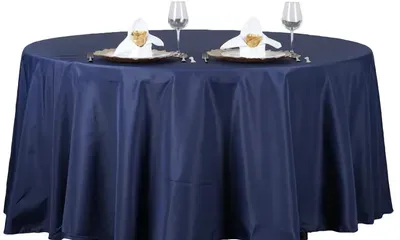 Round table with a navy blue tablecloth, set for two with plates, napkins, and wine glasses.