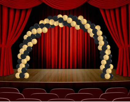 A stage with a balloon arch of gold and black. Red curtains backdrop.
