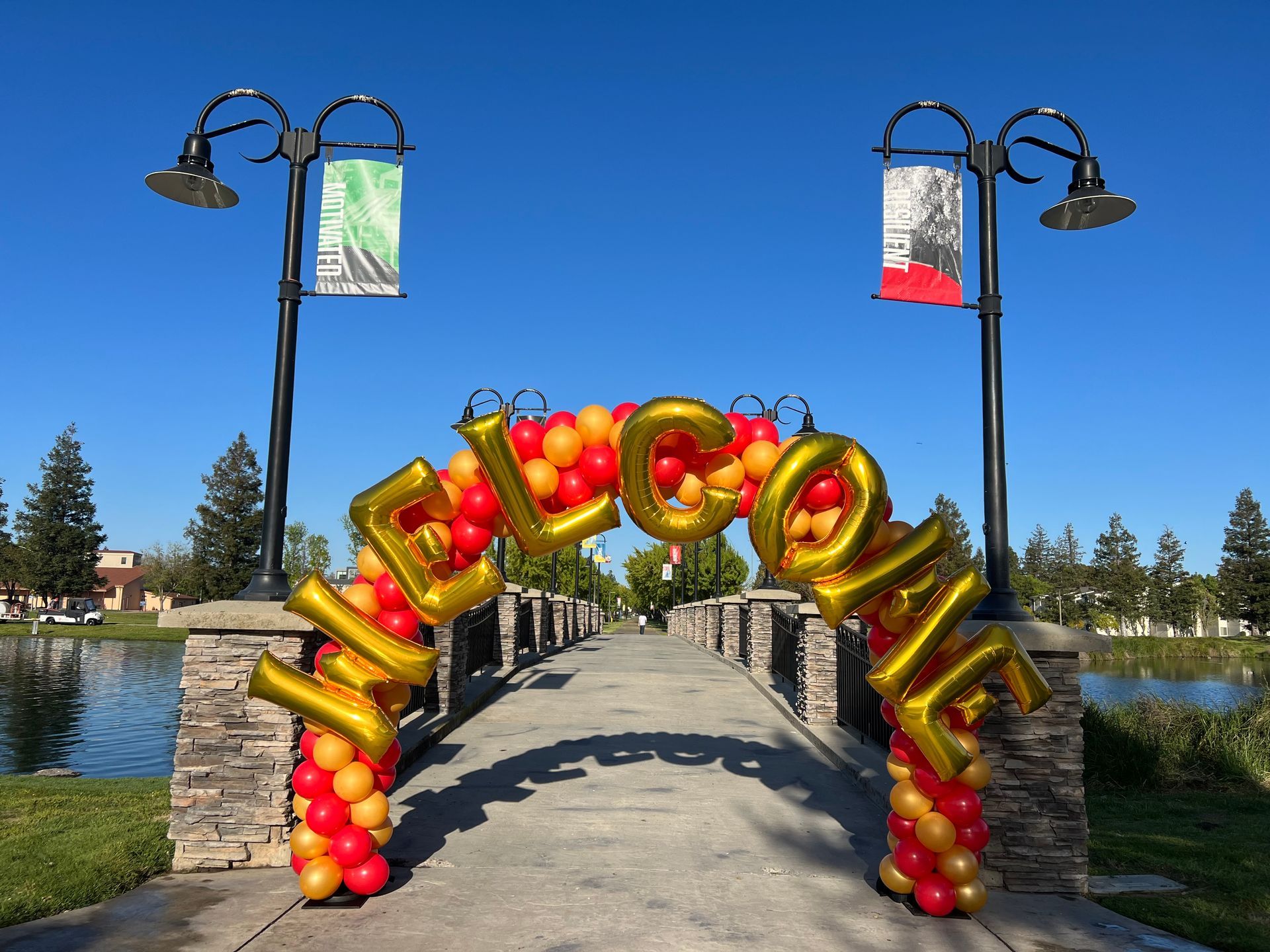Welcome arch made of balloons over a bridge in a park, gold 