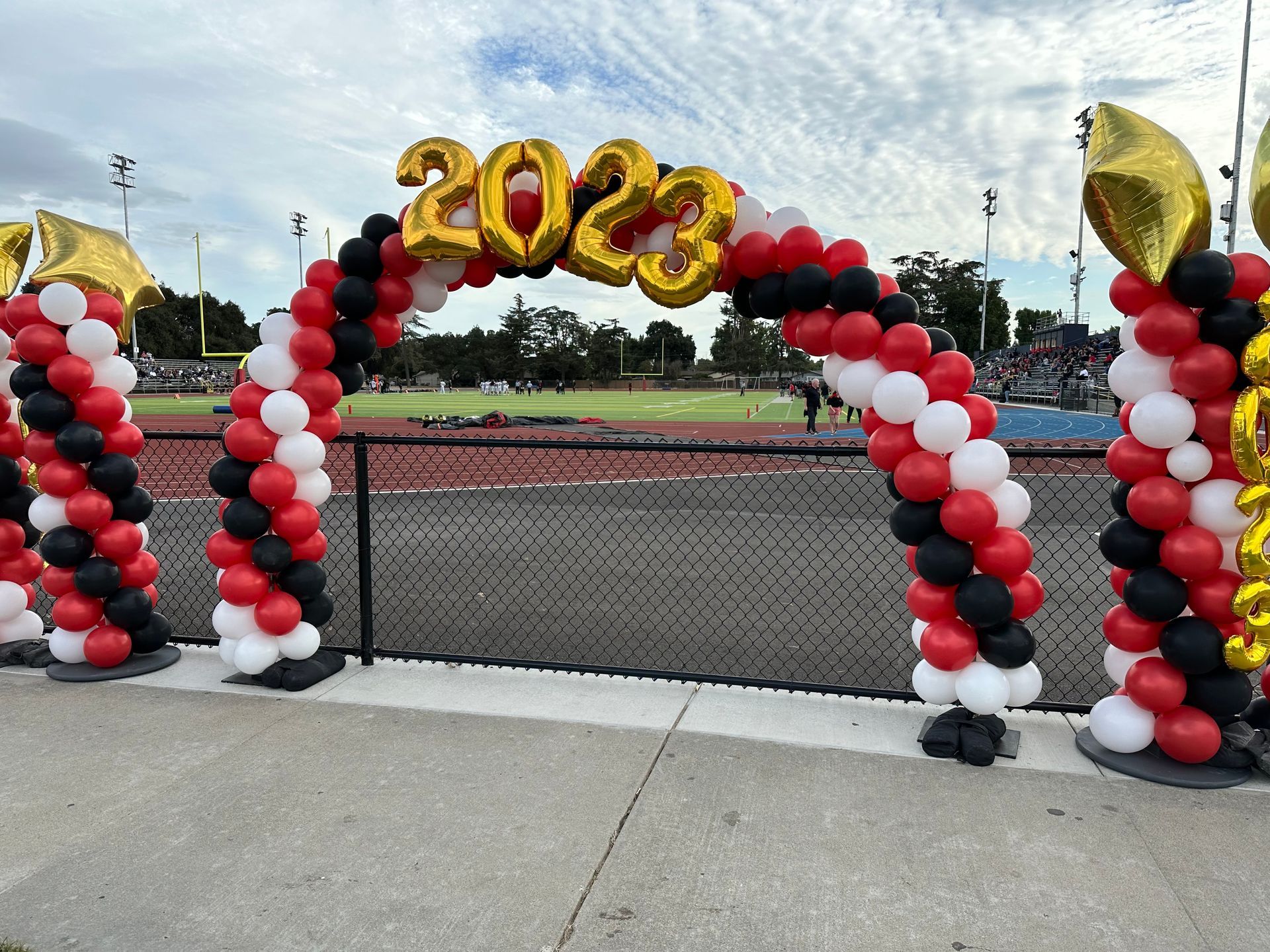 Graduation arch with red, black, and white balloons; gold 
