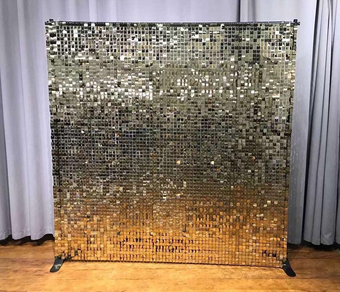 Gold sequin backdrop. Rectangular, the top is silver, fading to gold at the bottom, supported by a black metal frame.