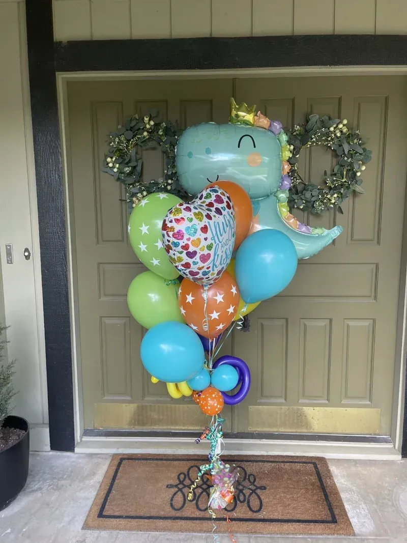 Dinosaur balloon bouquet in front of a door, including heart, star, and round balloons.