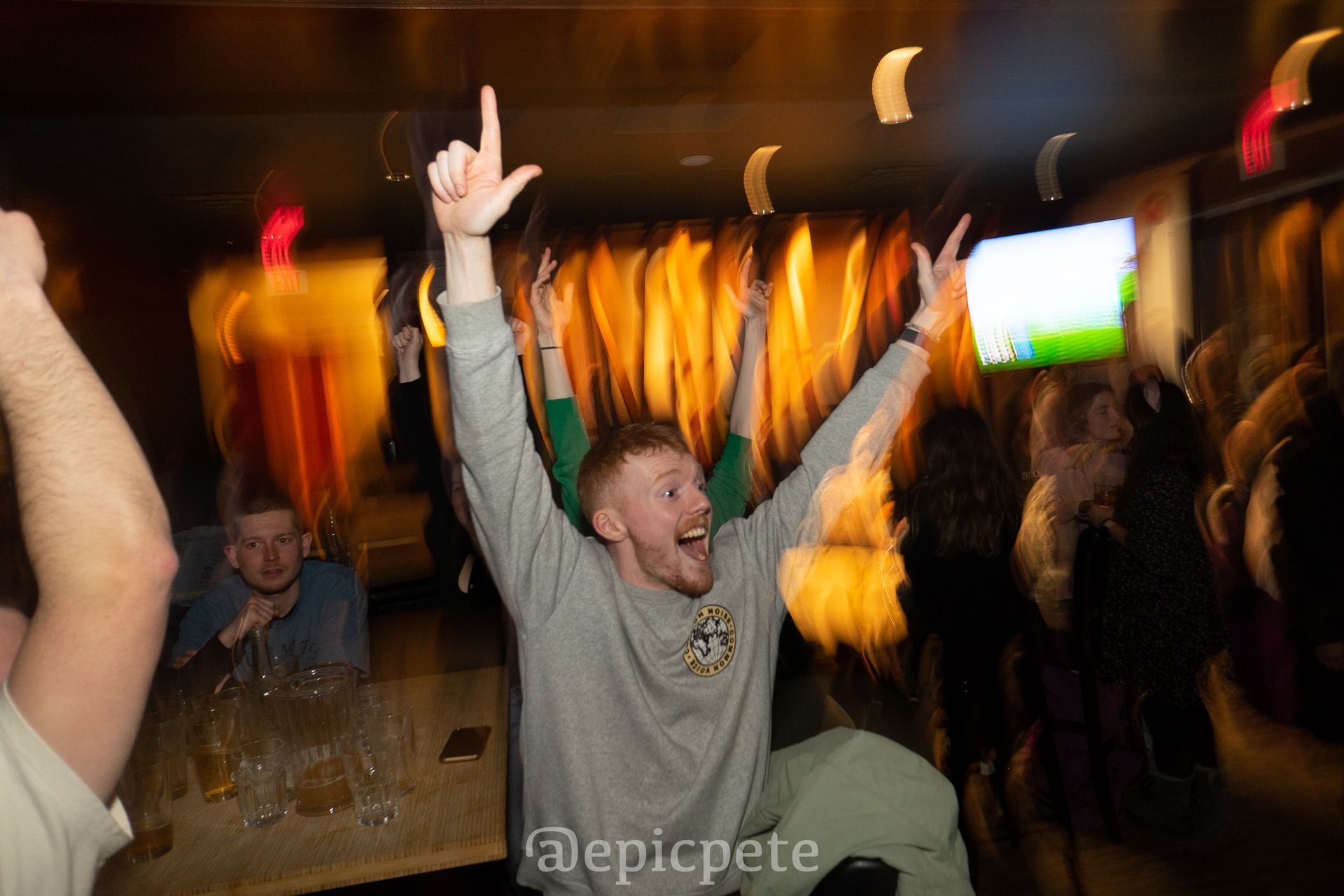 A man is dancing in a club with his arms in the air.
