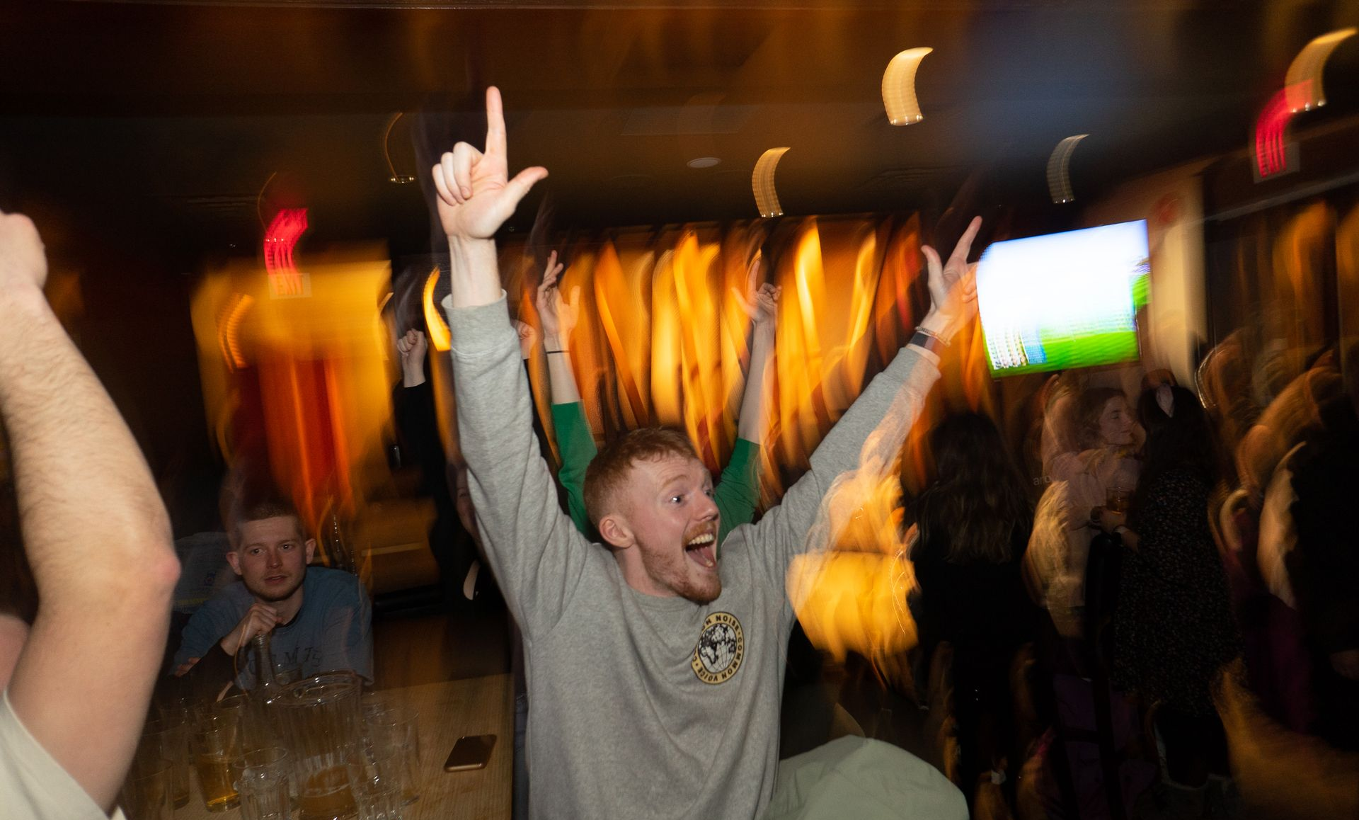 A man is dancing in a club with his arms in the air.