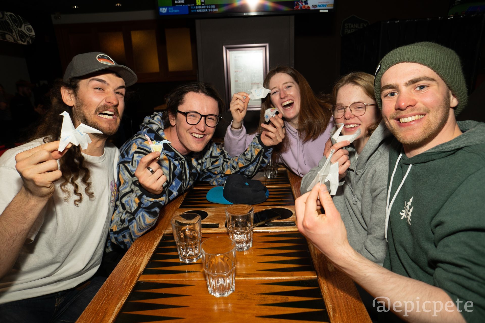 A group of people are sitting at a table holding nintendo wii controllers.