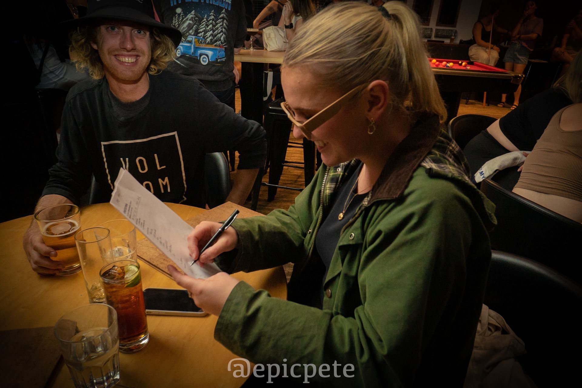 A woman is sitting at a table writing on a piece of paper.