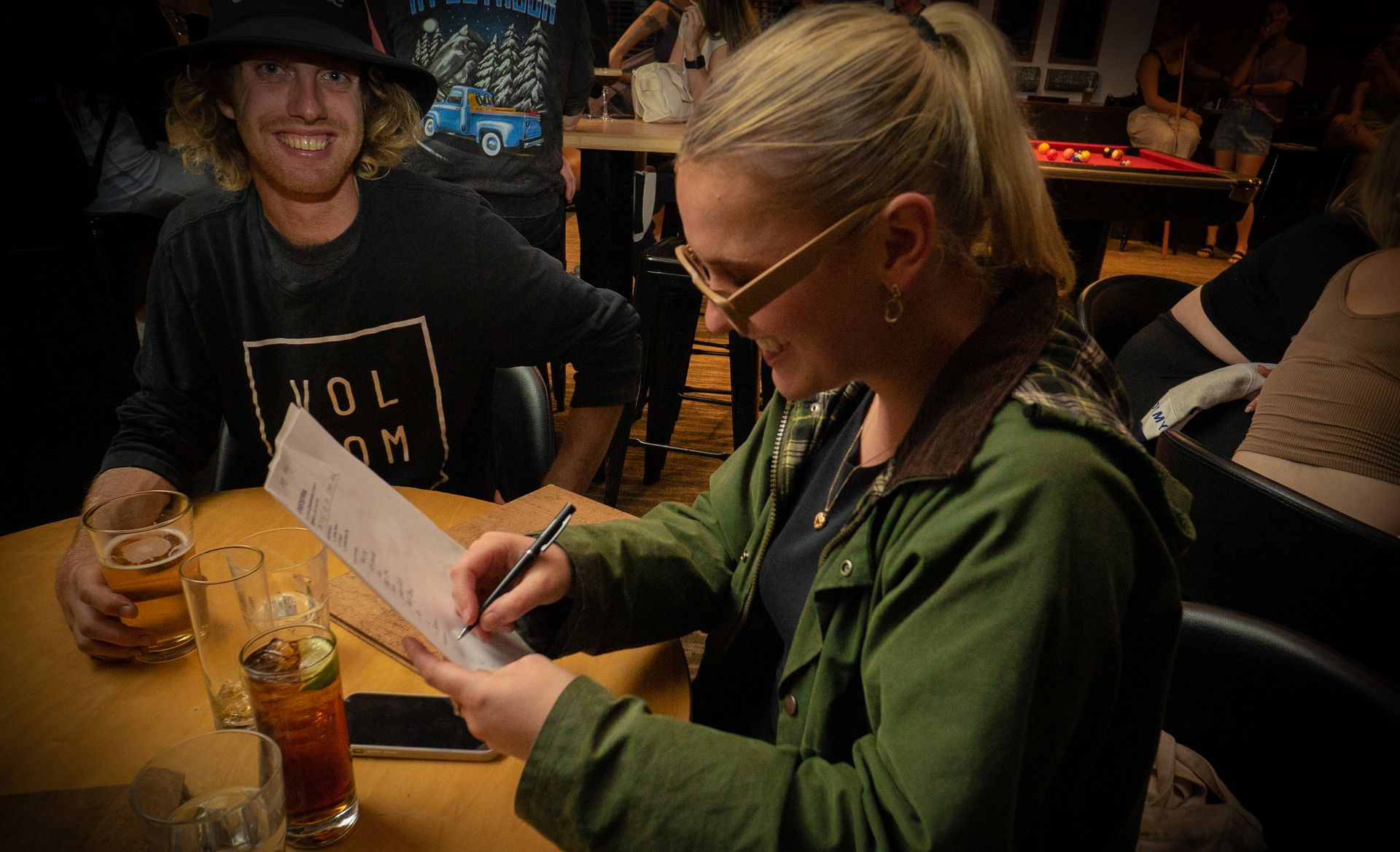 A woman is sitting at a table writing on a piece of paper.