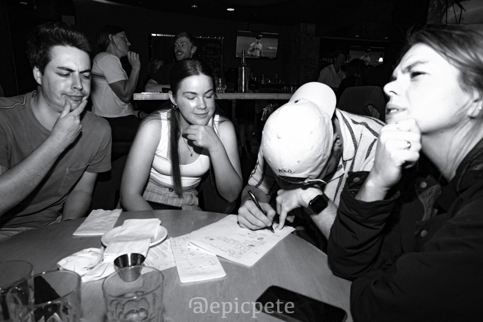 A black and white photo of a group of people sitting at a table.