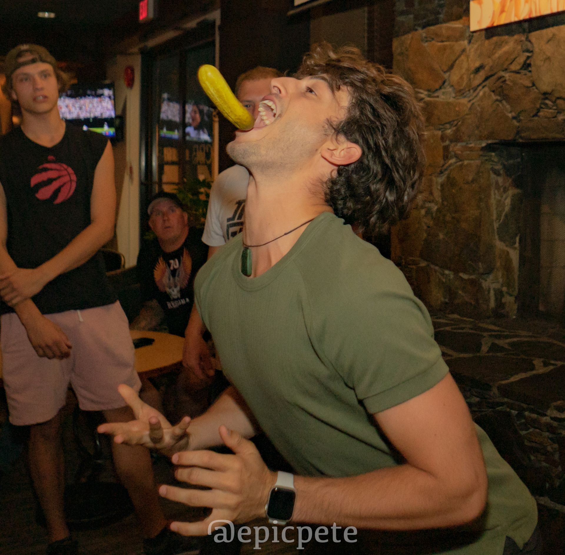 A man is holding a banana in his mouth and the photo was taken by epicpete