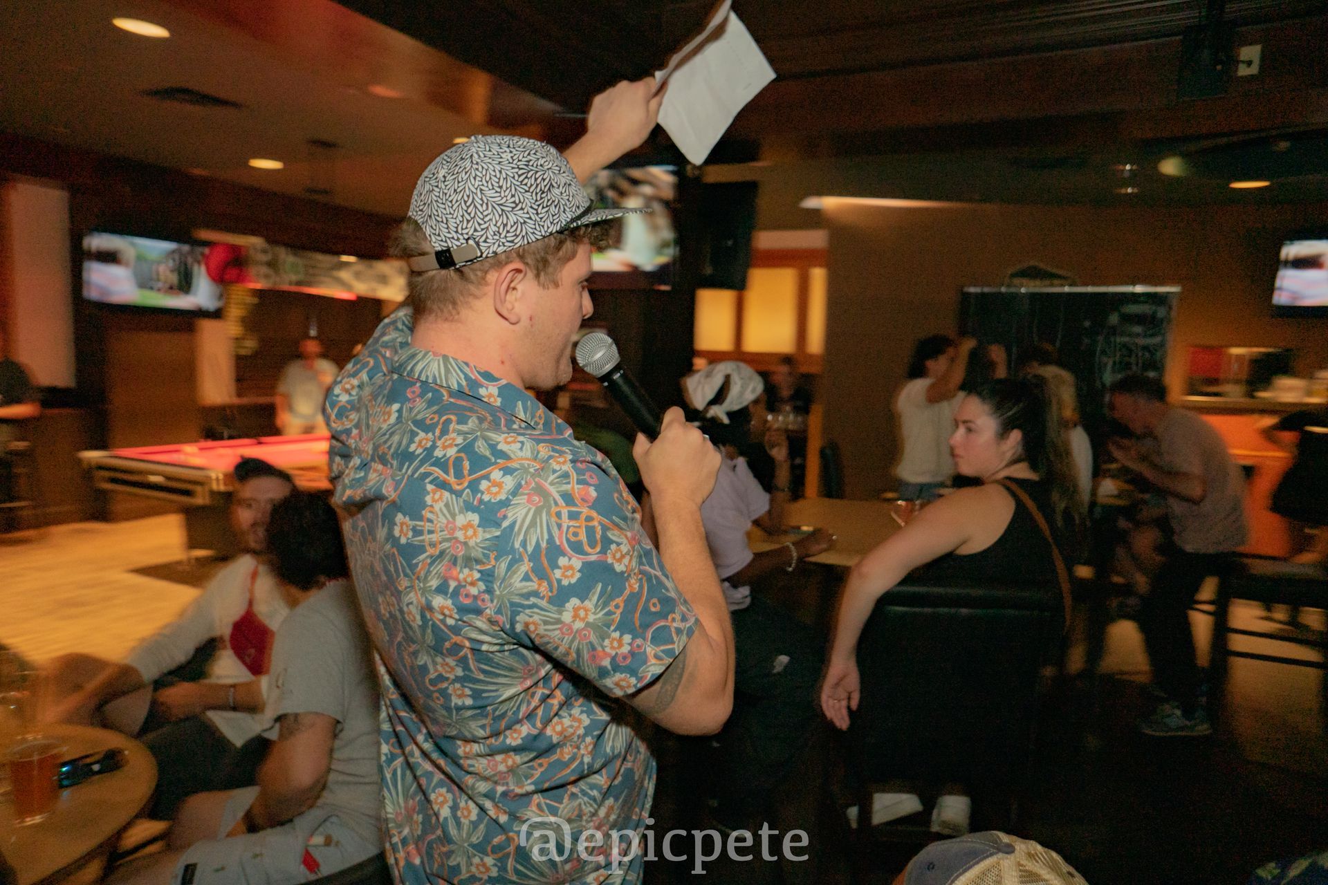 A man is holding a microphone in front of a crowd of people.