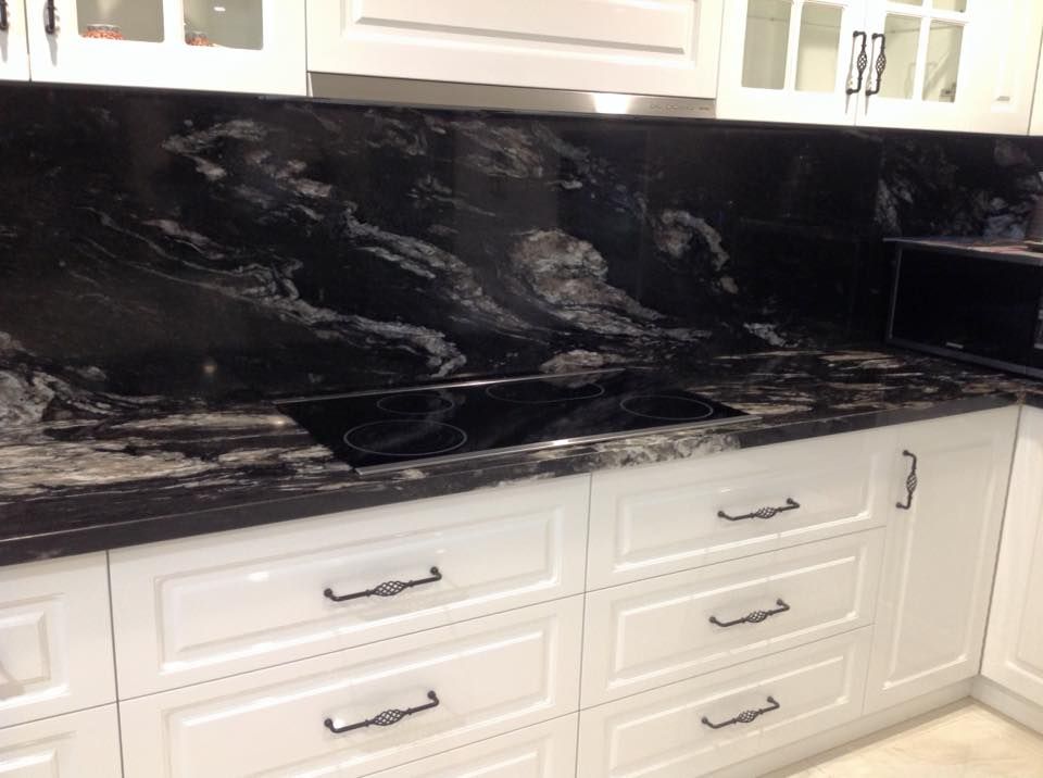 A kitchen with black granite countertops and white cabinets.