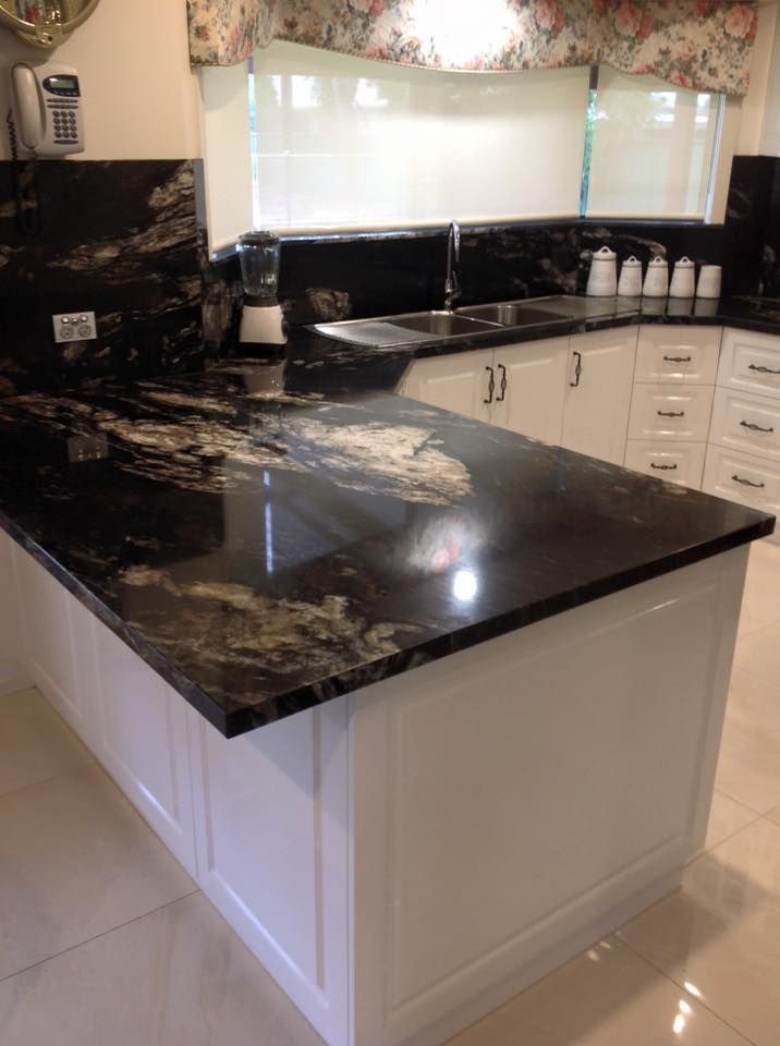 A kitchen with black granite counter tops and white cabinets