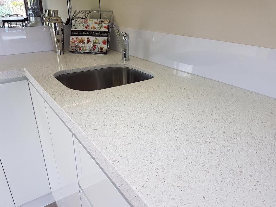 A kitchen counter with a sink and white cabinets