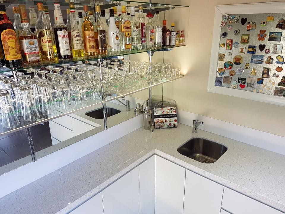 A bar with bottles and glasses on shelves and a sink