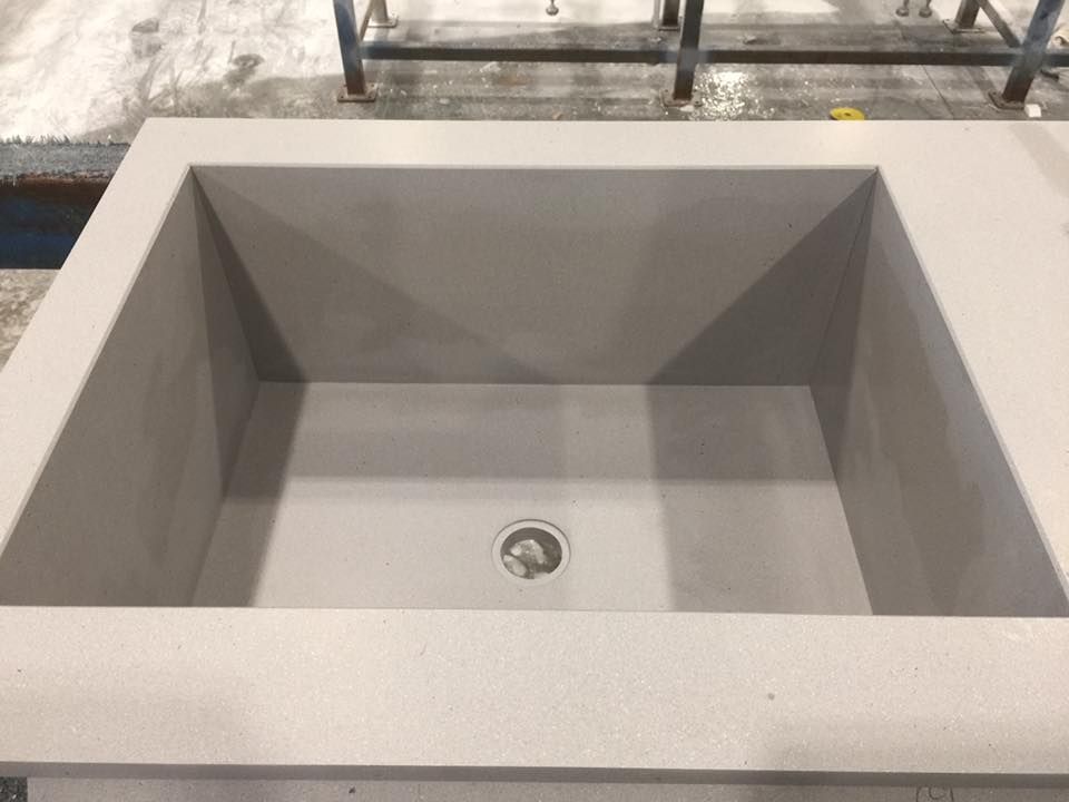 A square sink with a drain hole in the middle is sitting on a table.