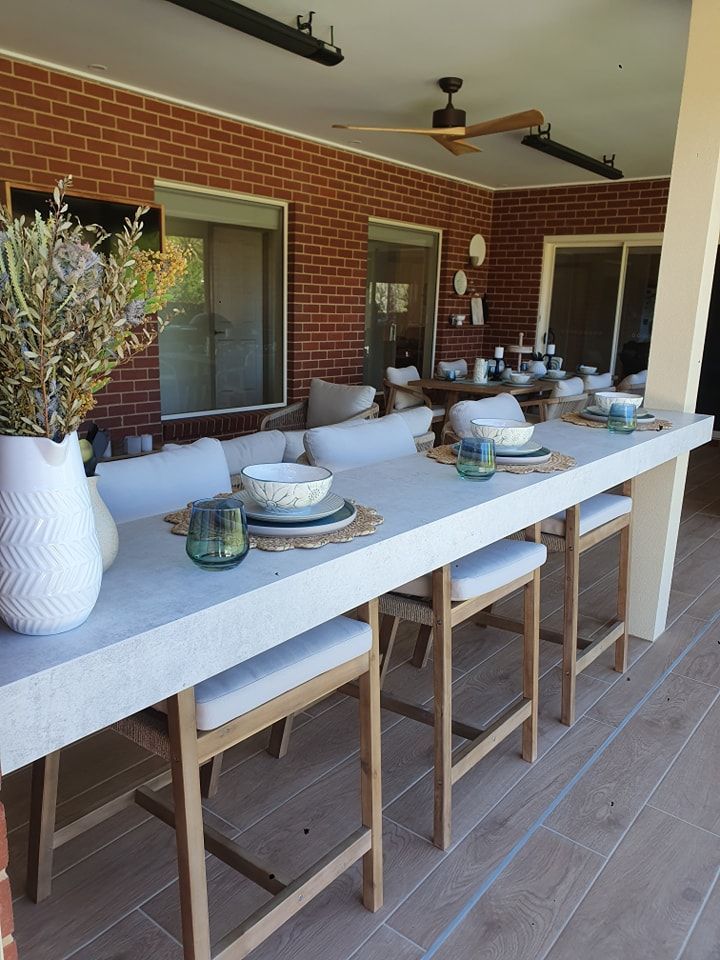 A patio with a long table and chairs and a ceiling fan