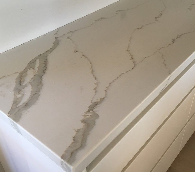 A close up of a white marble countertop in a kitchen.