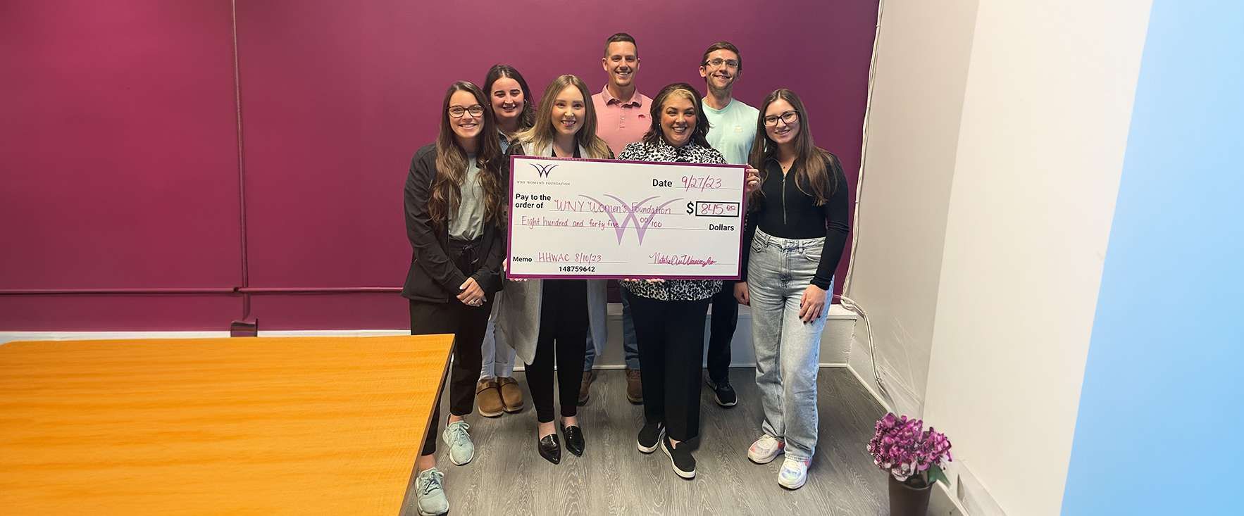 A group of people are standing next to each other holding a large check.