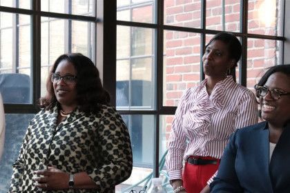 Three women are sitting in front of a window in a room.