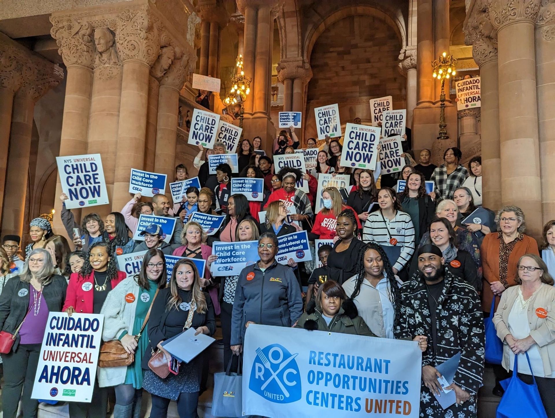 A large group of people holding signs including one that says restaurant opportunities centers united