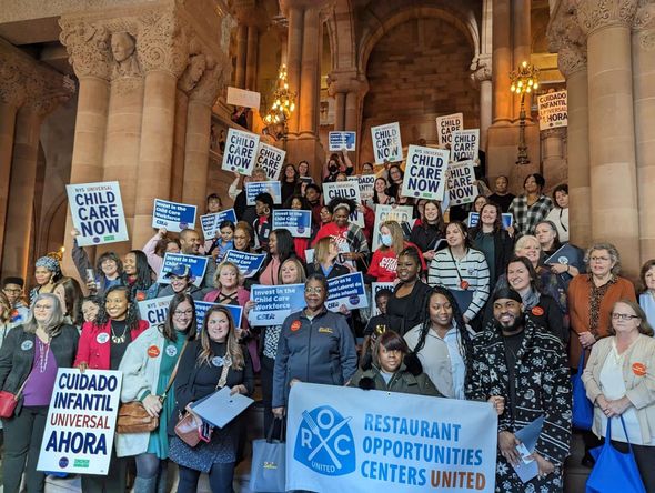 A large group of people holding signs including one that says restaurant opportunities centers united