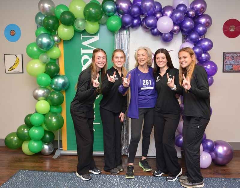 A group of women are posing for a picture in front of balloons.