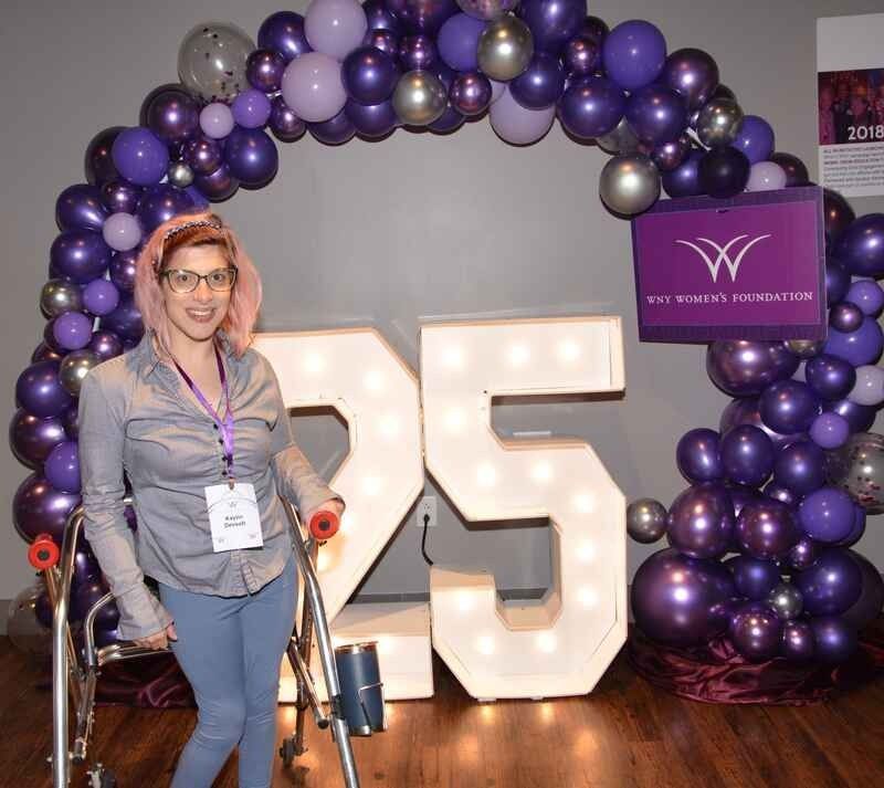 A woman in a wheelchair is standing in front of a large number 25
