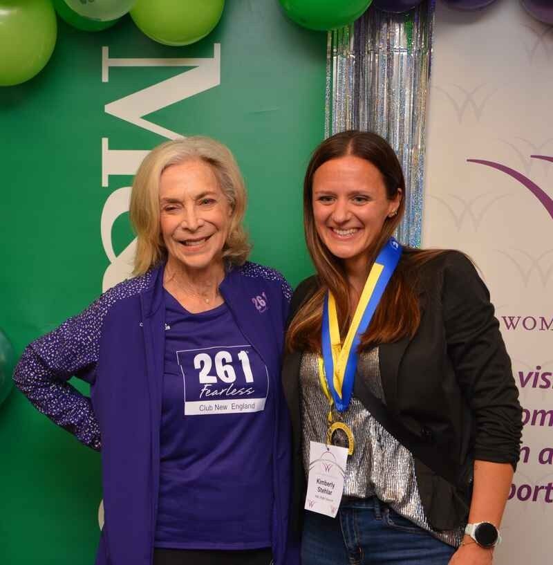 Two women are posing for a picture and one has the number 261 on her shirt