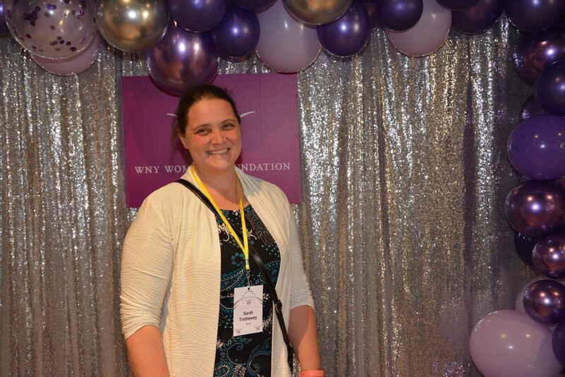 A woman is standing in front of a wall of balloons.