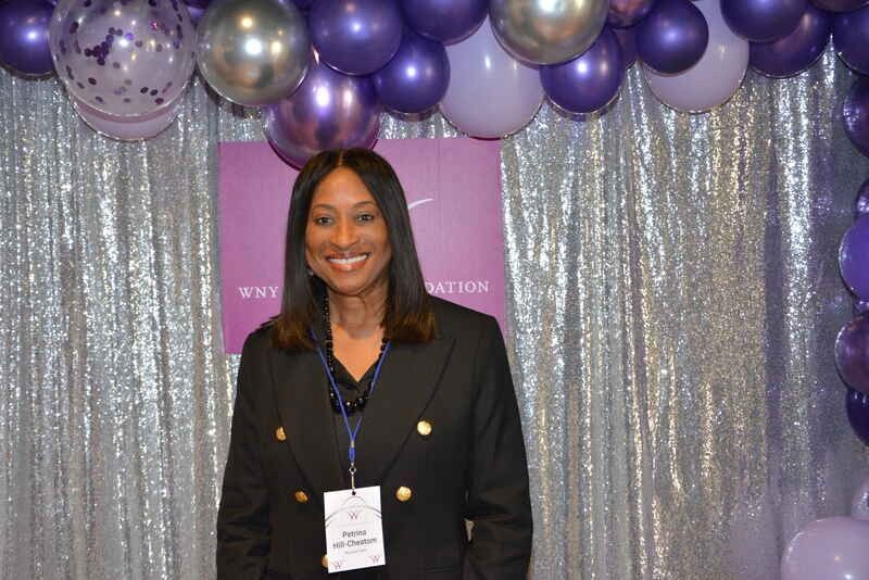 A woman is standing in front of a wall of balloons.
