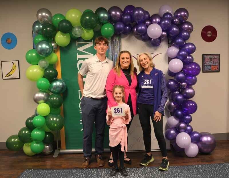 A group of people are posing for a picture in front of balloons.