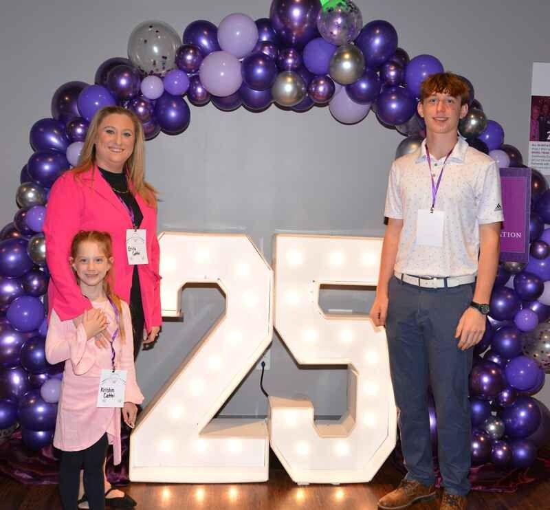 A group of people standing in front of a large number 25