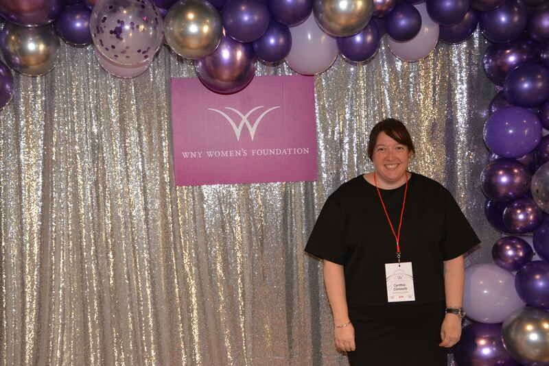 A woman is standing in front of a wall of balloons.