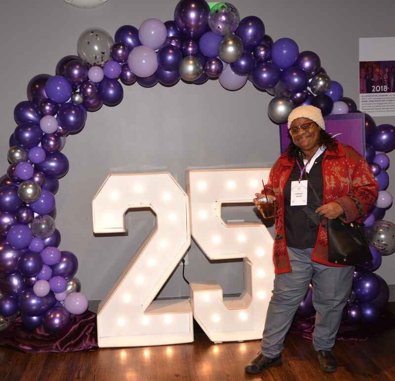 A woman is standing in front of a sign that says 25