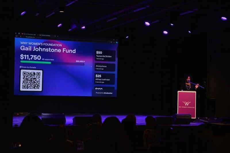 A man is giving a speech in front of a screen that says gail johnson fund