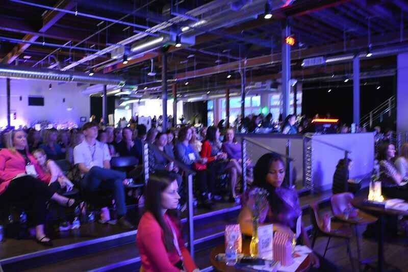 A large group of people are sitting in a room watching a presentation.